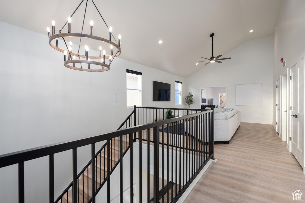 Hallway featuring an upstairs landing, light wood-style flooring, high vaulted ceiling, a chandelier, and recessed lighting