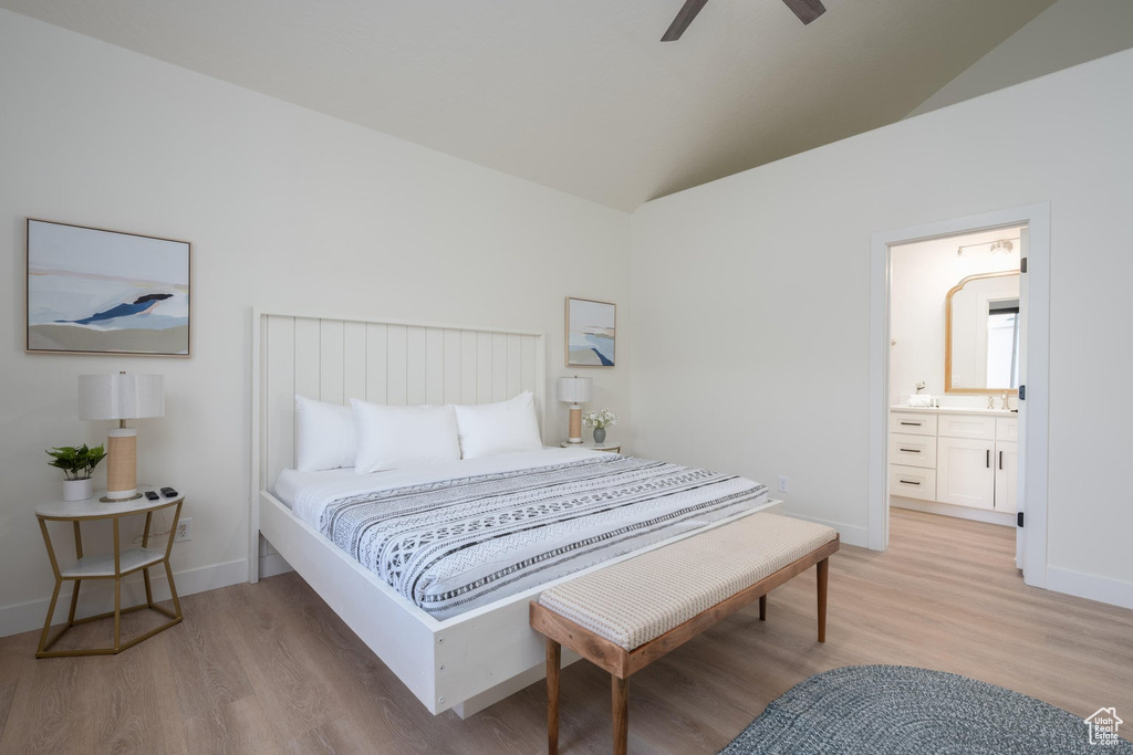 Bedroom with vaulted ceiling, light wood-type flooring, ensuite bath, and a ceiling fan