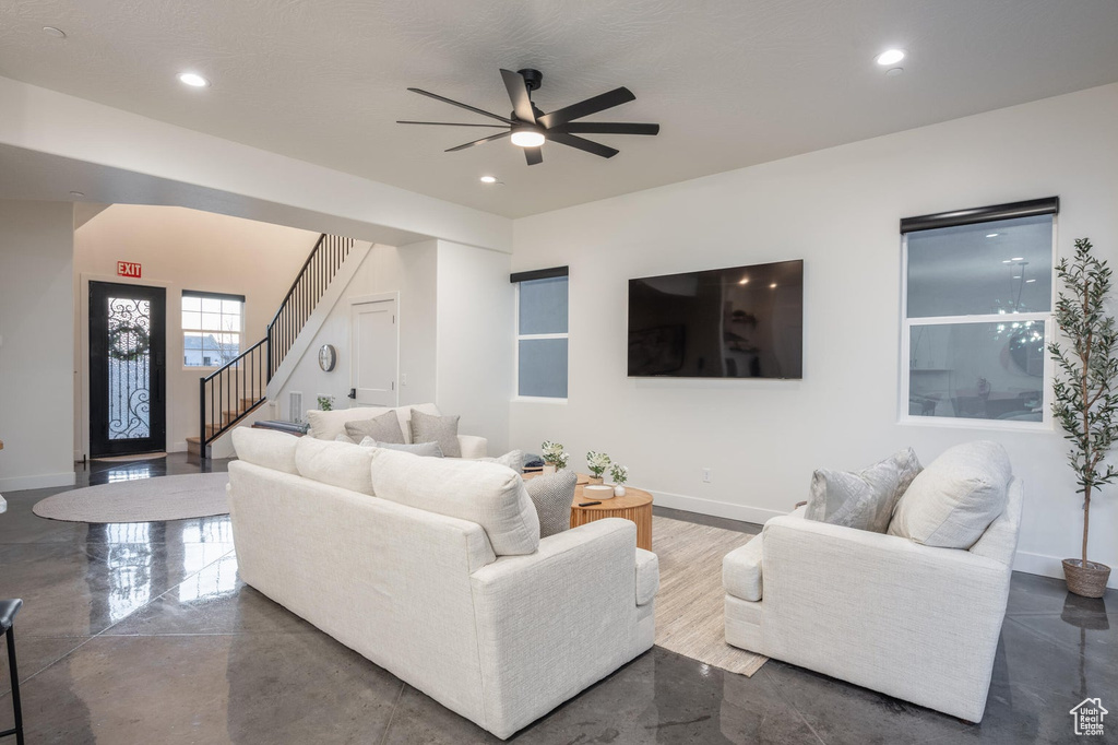 Living area with a ceiling fan, recessed lighting, and stairs