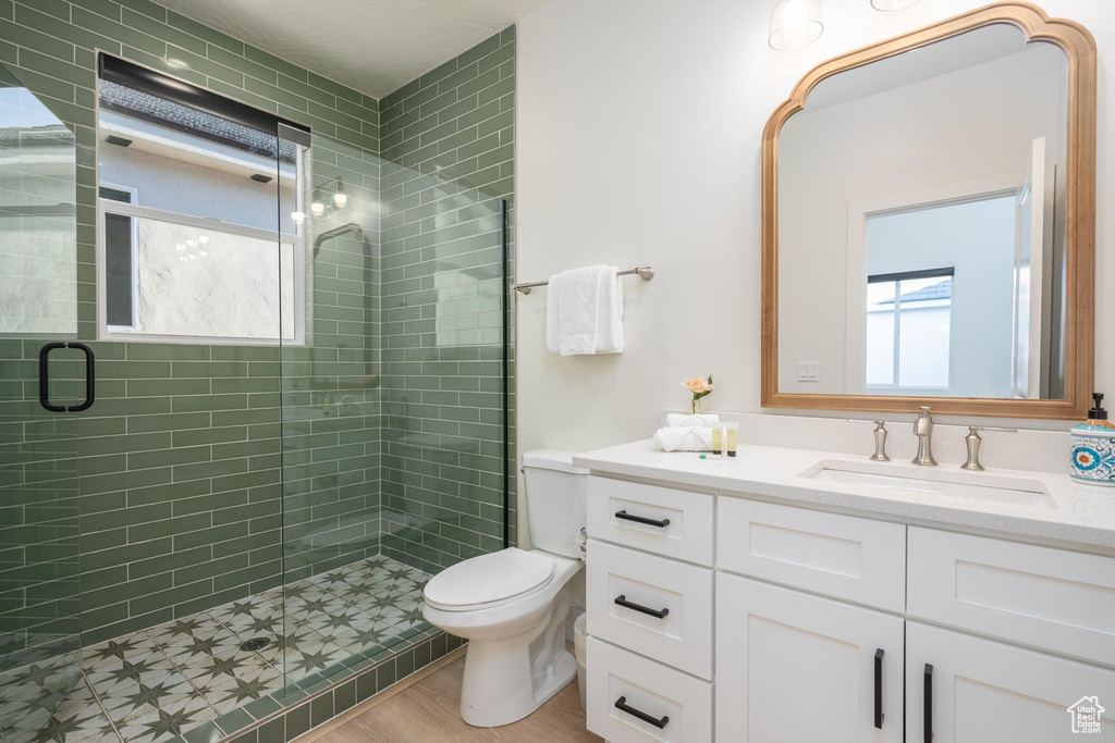 Bathroom featuring plenty of natural light, vanity, a stall shower, and wood finished floors