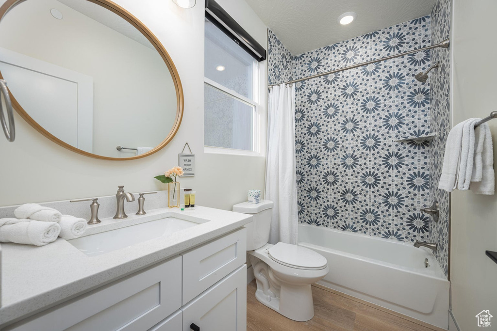Bathroom featuring shower / bathtub combination with curtain, vanity, wood finished floors, and recessed lighting