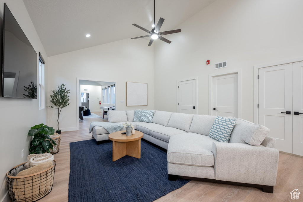 Living room featuring high vaulted ceiling, ceiling fan, light wood finished floors, and recessed lighting