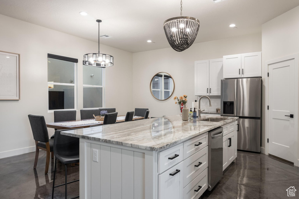 Kitchen featuring appliances with stainless steel finishes, a chandelier, finished concrete flooring, a kitchen bar, and recessed lighting