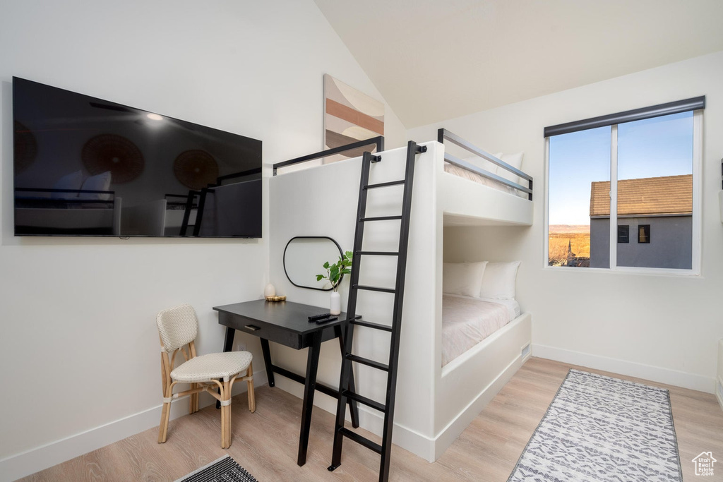 Bedroom with wood finished floors and high vaulted ceiling