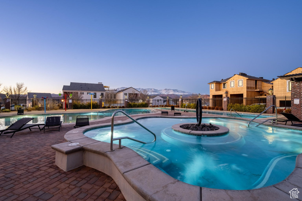Pool at dusk with a community pool, a residential view, and a patio area