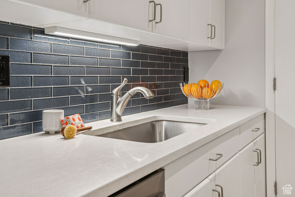 Kitchen view of tasteful backsplash, white cabinets, and light countertops