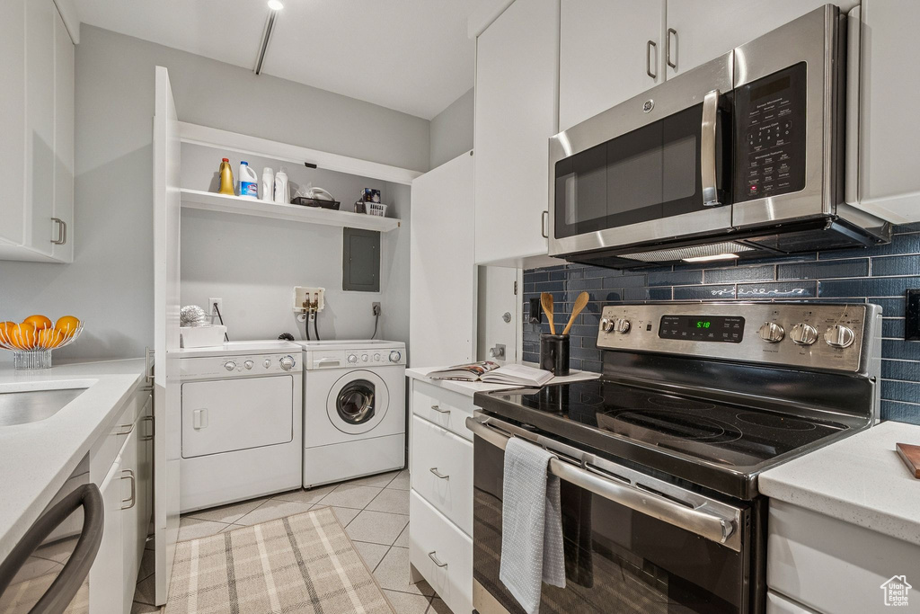 Kitchen with appliances with stainless steel finishes, independent washer and dryer, light countertops, white cabinetry, and backsplash