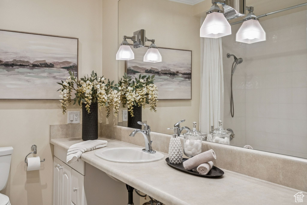 Bathroom featuring tiled shower and vanity