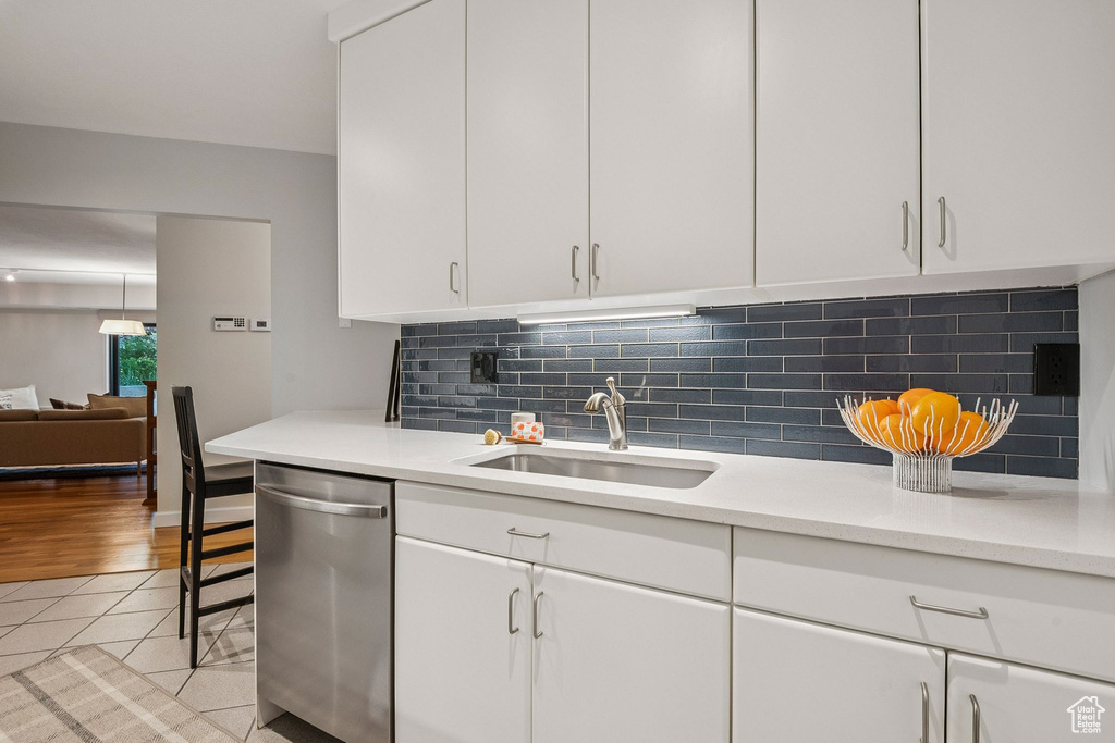 Kitchen with stainless steel dishwasher, light countertops, and white cabinets