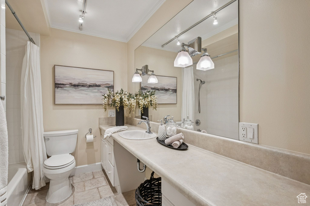 Bathroom featuring vanity, rail lighting, shower / tub combo, ornamental molding, and stone tile flooring