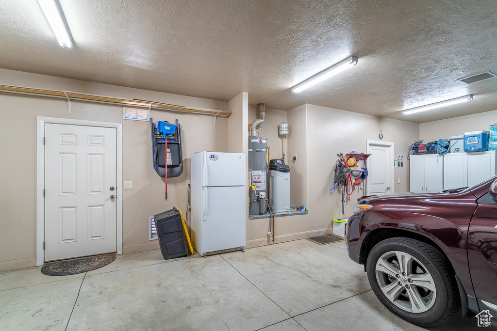 Garage featuring freestanding refrigerator and water heater