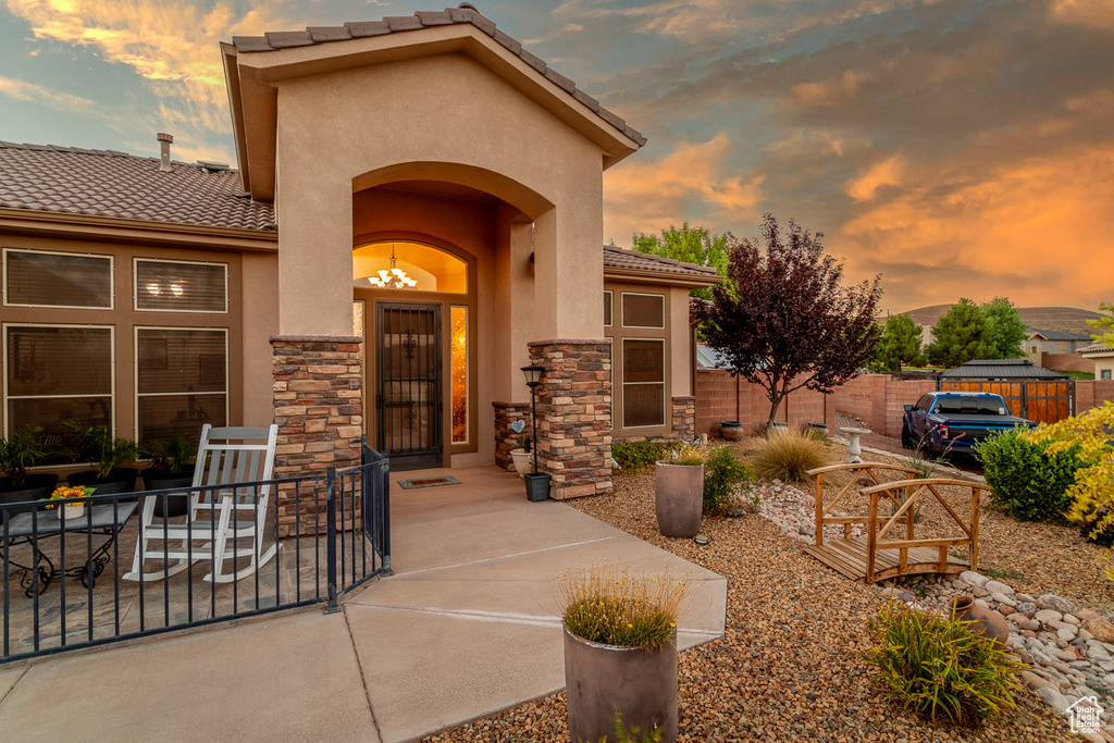 Exterior entry at dusk with a tiled roof, stucco siding, and stone siding