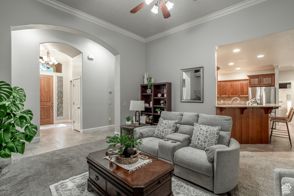 Living area with ceiling fan, ornamental molding, arched walkways, a chandelier, and recessed lighting