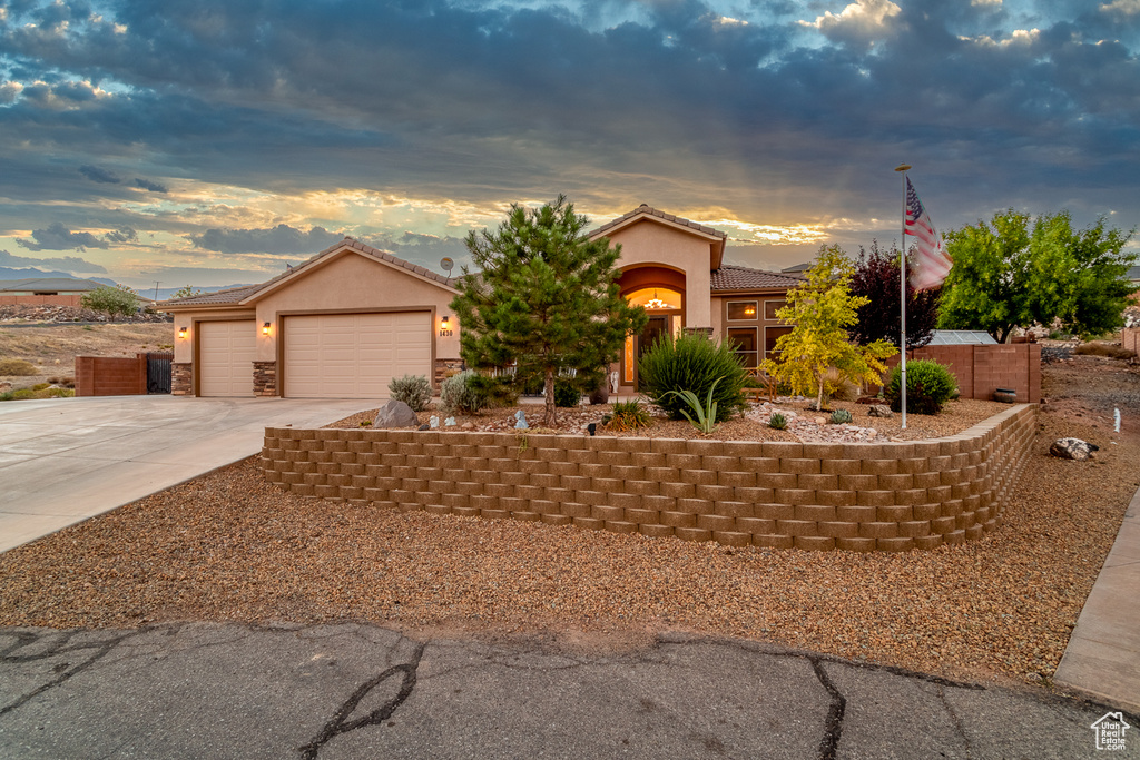 View of front of property with concrete driveway, stucco siding, a tiled roof, and an attached garage
