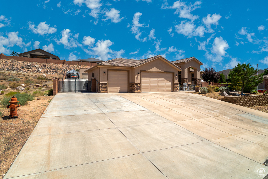 Mediterranean / spanish house featuring a gate, stone siding, a garage, concrete driveway, and stucco siding