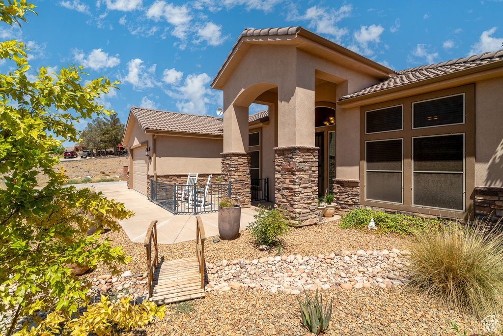 View of side of property with stucco siding, a tiled roof, and stone siding
