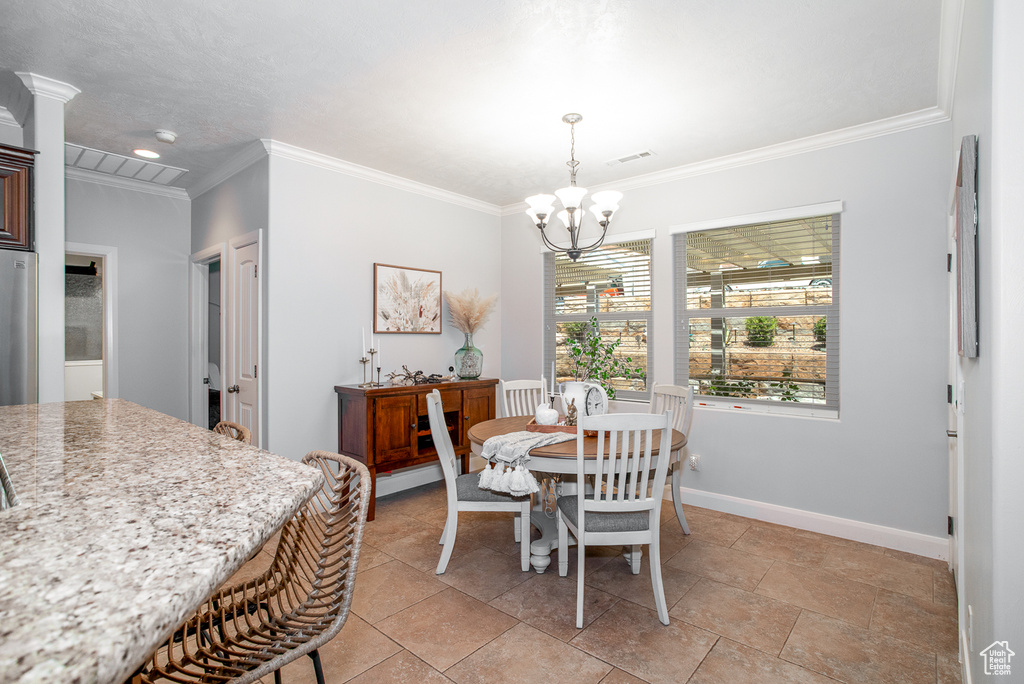Dining area with ornamental molding and a chandelier
