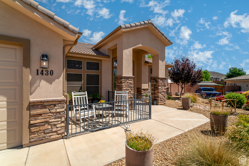 View of exterior entry with stone siding, stucco siding, and a tile roof