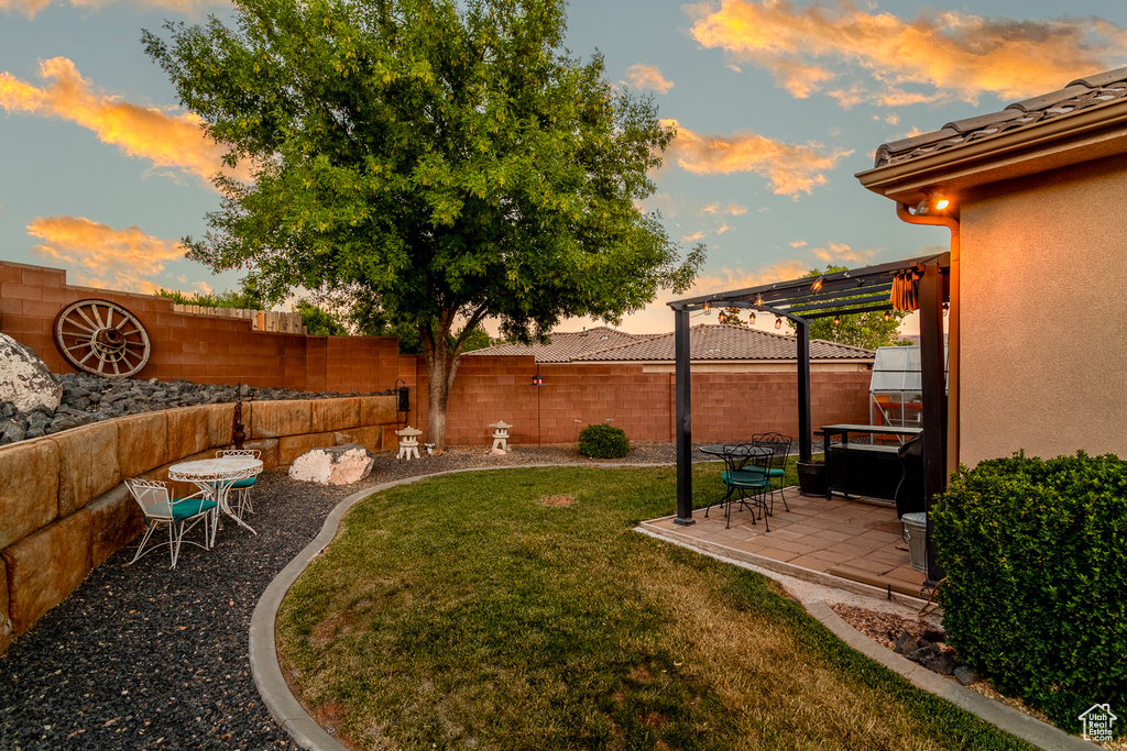 Yard at dusk featuring a patio area, a fenced backyard, and a pergola