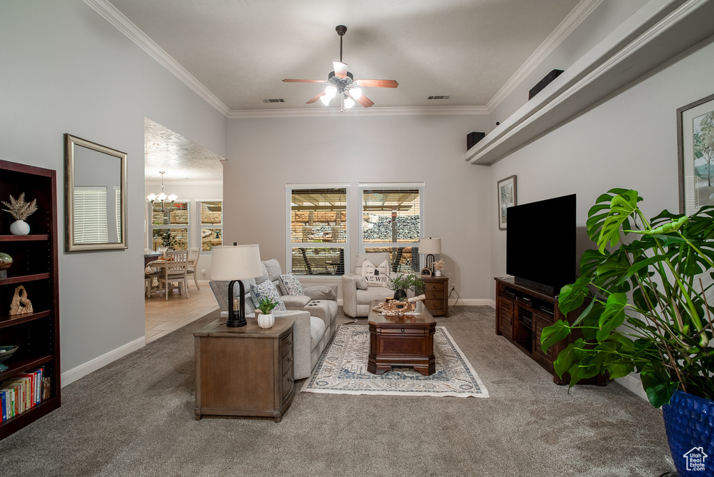 Carpeted living room featuring a ceiling fan, ornamental molding, and a chandelier
