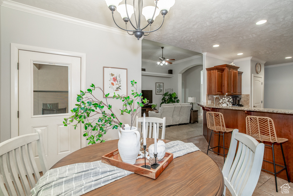 Dining room featuring ornamental molding, a chandelier, recessed lighting, ceiling fan, and arched walkways