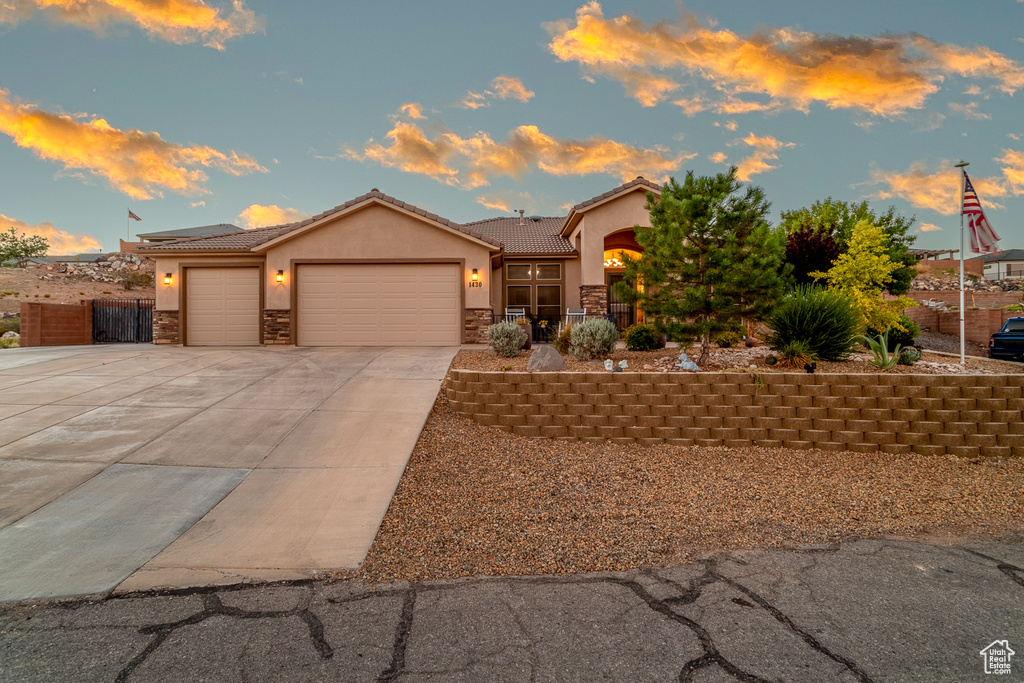 View of front facade featuring stone siding, an attached garage, stucco siding, concrete driveway, and a tile roof