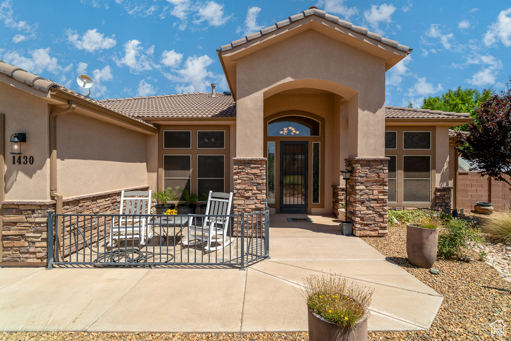 Entrance to property featuring stone siding, a tile roof, and stucco siding