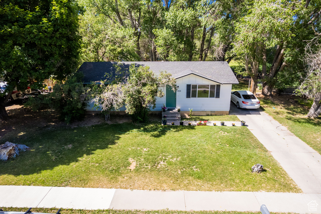 View of front of property featuring a front yard, roof with shingles, and driveway