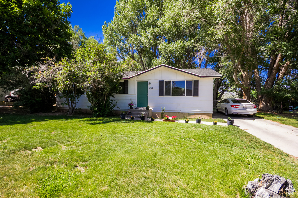 View of front of property featuring a front yard, board and batten siding, and driveway