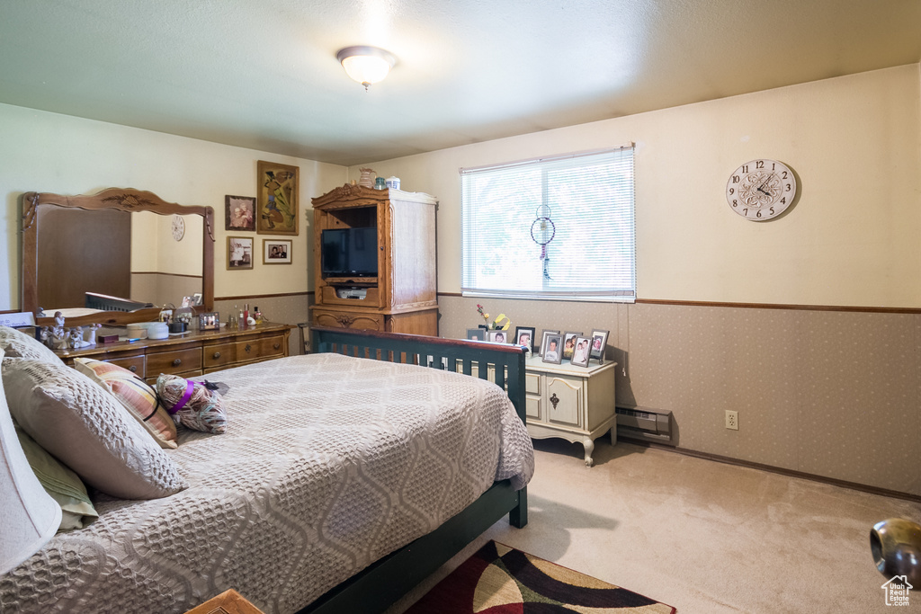 Carpeted bedroom featuring baseboard heating and wallpapered walls