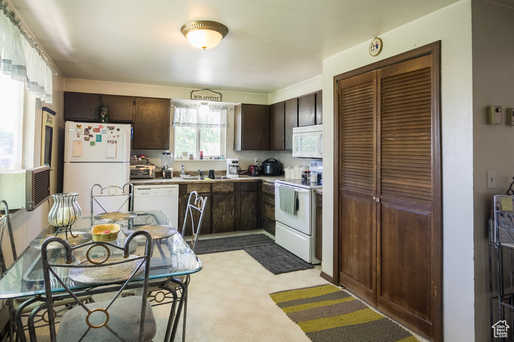 Kitchen with white appliances, dark brown cabinets, and light countertops