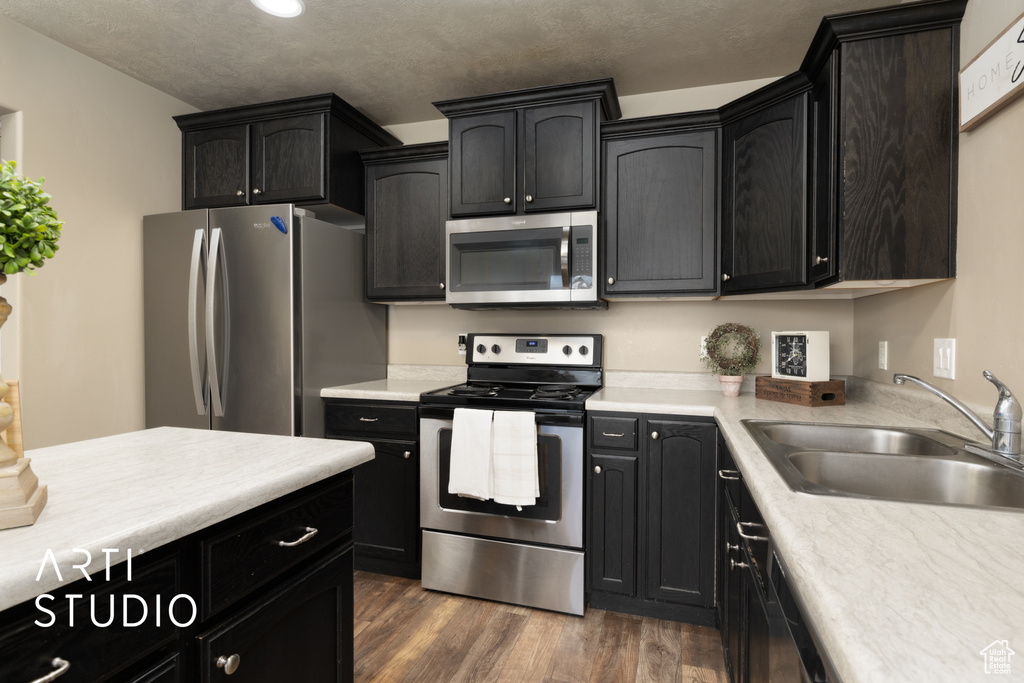 Kitchen featuring stainless steel appliances, dark wood-type flooring, and light countertops