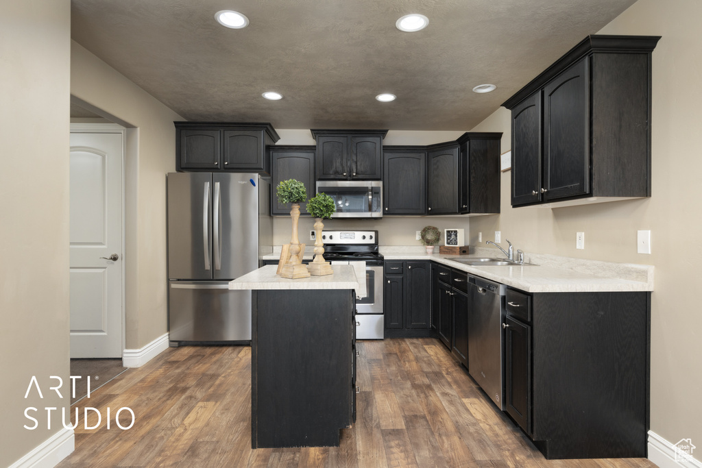 Kitchen with stainless steel appliances, a center island, recessed lighting, dark wood finished floors, and light countertops