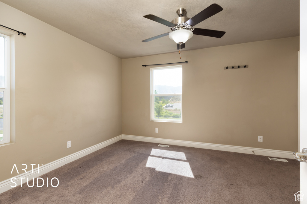 Carpeted spare room featuring baseboards and ceiling fan