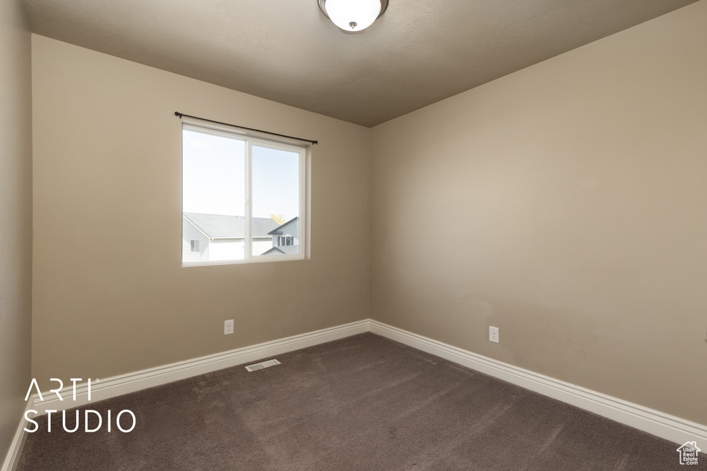 Spare room with dark colored carpet and baseboards