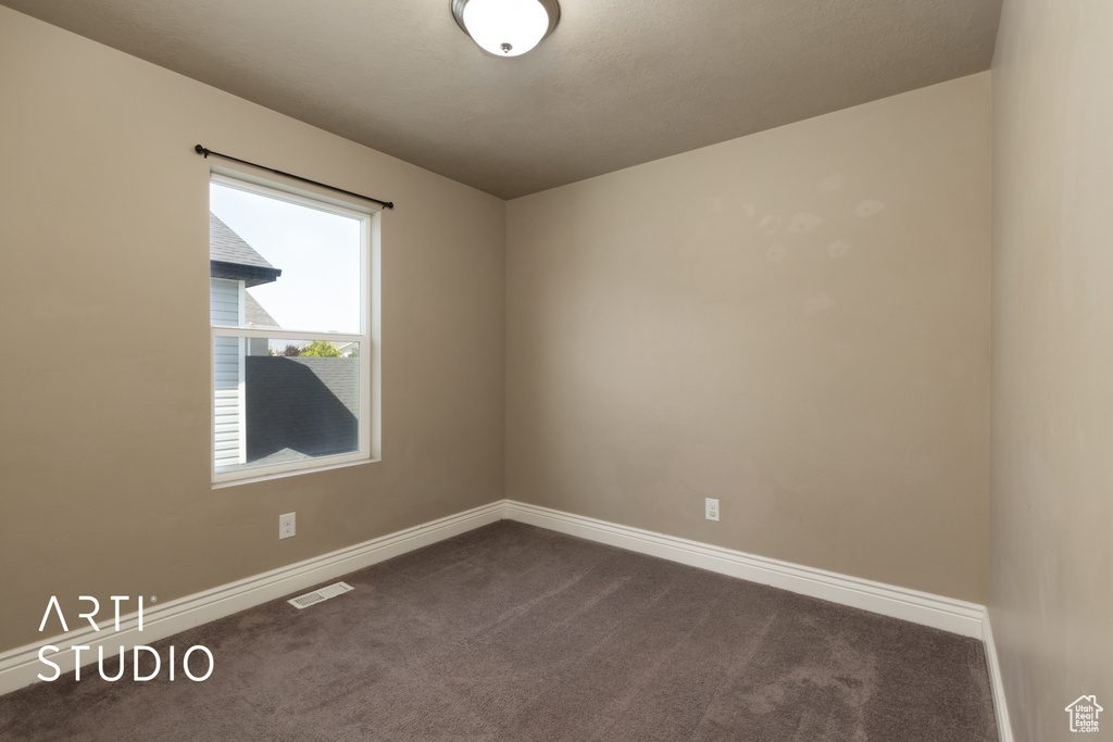 Empty room with dark colored carpet and baseboards