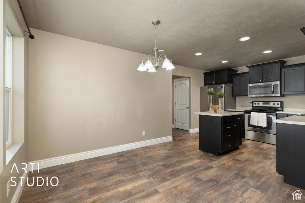 Kitchen featuring appliances with stainless steel finishes, recessed lighting, a kitchen island, light countertops, and dark wood-type flooring