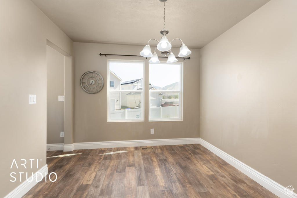 Unfurnished dining area featuring a chandelier and dark wood-style flooring