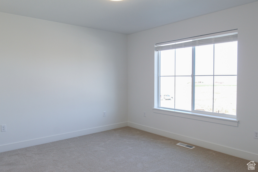 Empty room featuring baseboards and light colored carpet