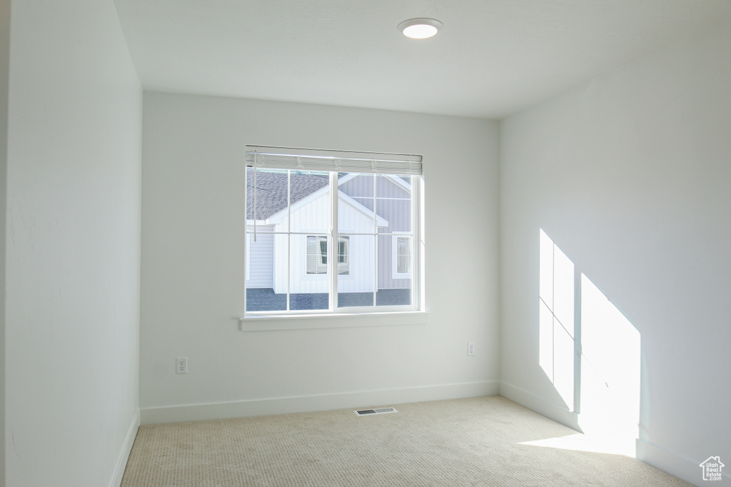 Unfurnished room featuring baseboards and light carpet