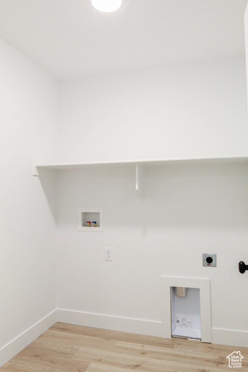 Washroom with electric dryer hookup, hookup for a washing machine, and light wood-type flooring