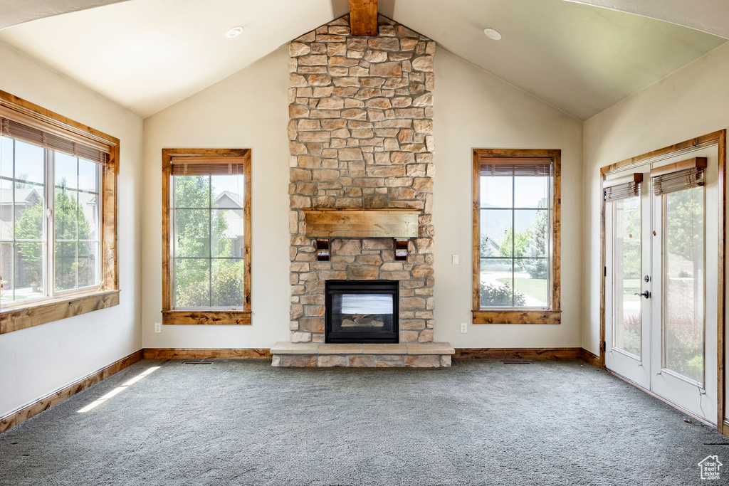 Unfurnished living room featuring carpet, a fireplace, and high vaulted ceiling