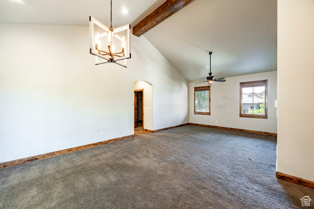 Empty room featuring beamed ceiling, arched walkways, carpet, a chandelier, and a ceiling fan