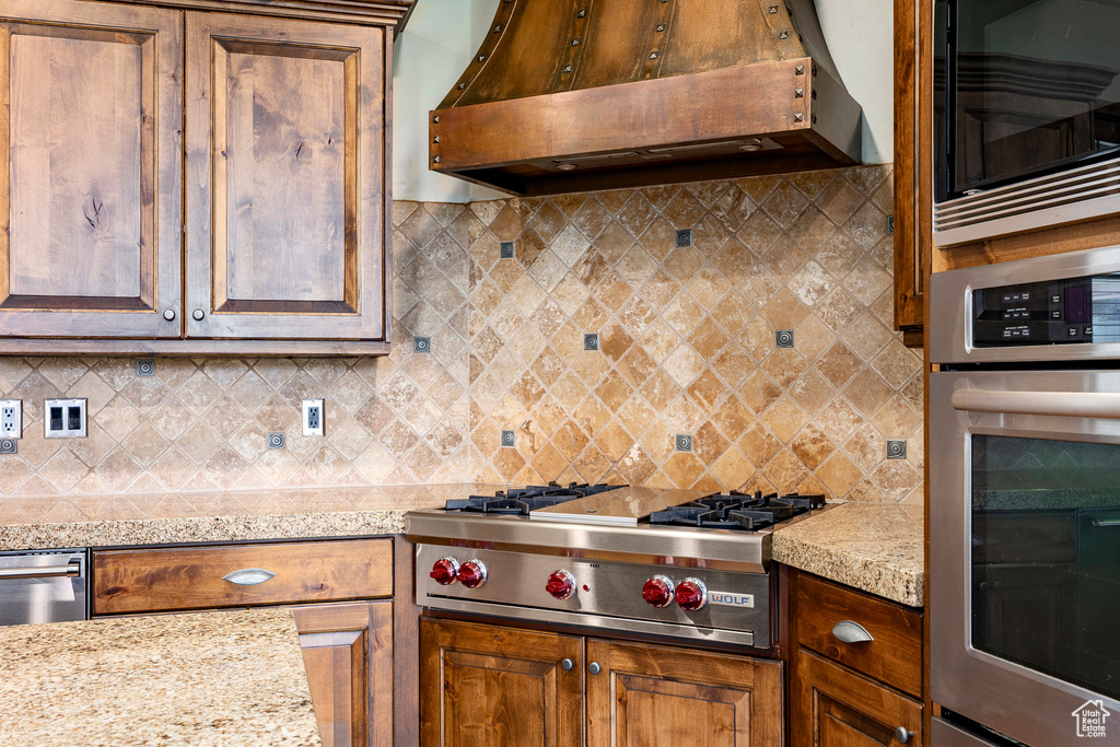 Kitchen featuring appliances with stainless steel finishes, under cabinet range hood, and tasteful backsplash