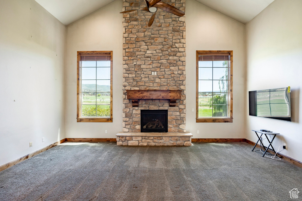 Unfurnished living room with healthy amount of natural light, a ceiling fan, carpet flooring, and high vaulted ceiling