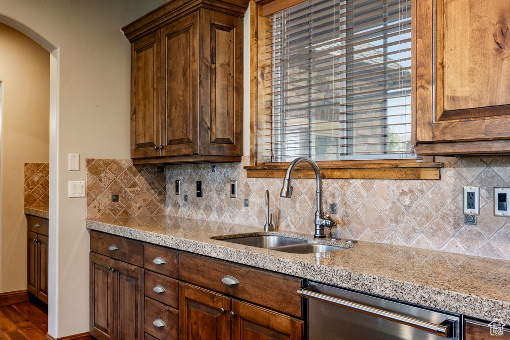 Kitchen with dishwasher, light stone countertops, and decorative backsplash