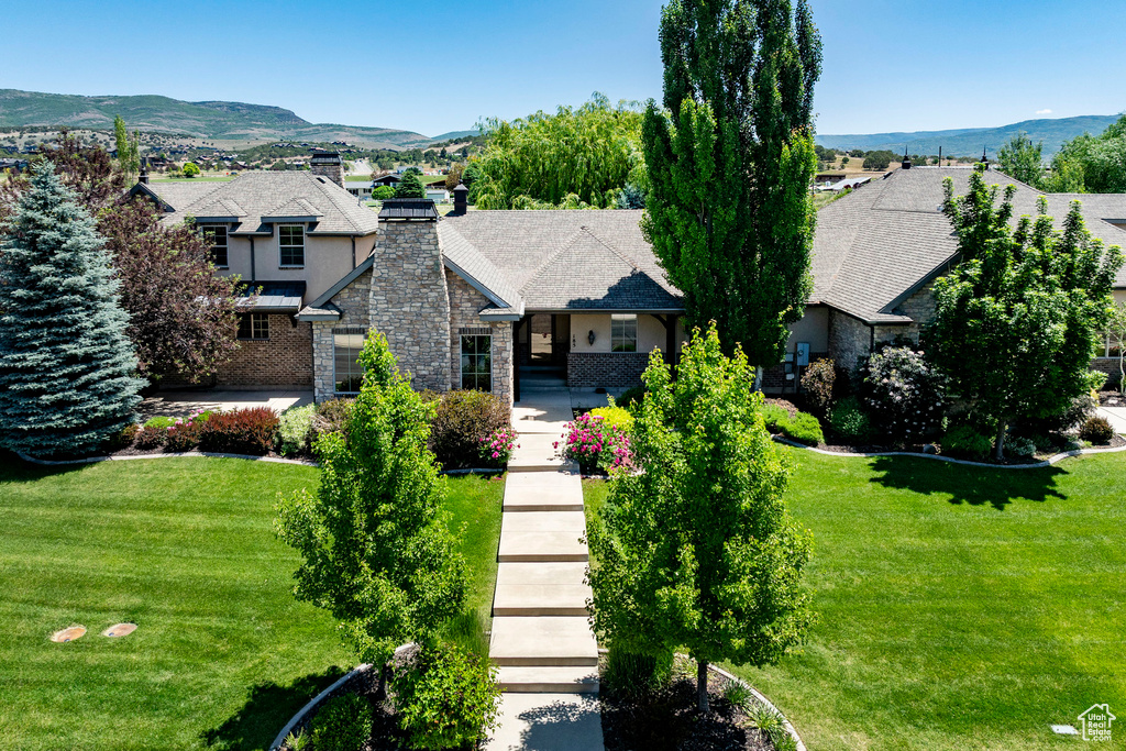 View of front of house featuring a front yard, a chimney, and a mountain view