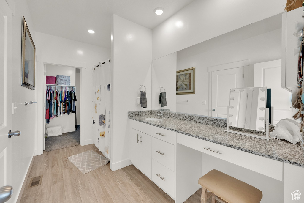 Bathroom with wood finished floors, vanity, and recessed lighting