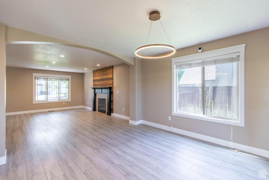 Unfurnished living room featuring light wood-style floors, a fireplace, arched walkways, and recessed lighting