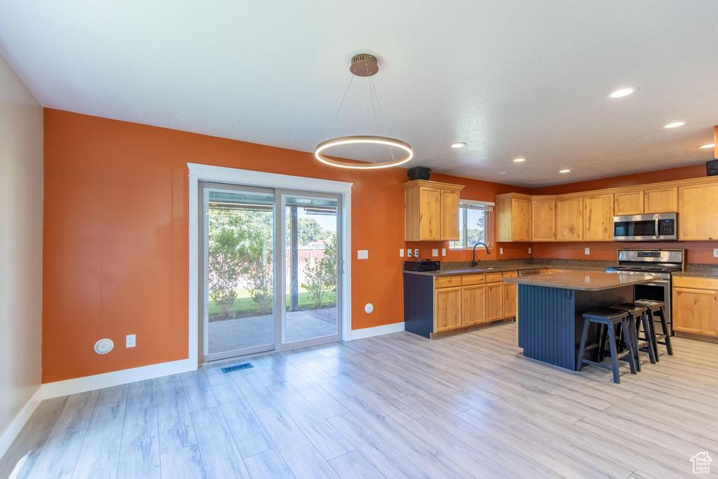 Kitchen with stainless steel appliances, plenty of natural light, a kitchen breakfast bar, light wood finished floors, and recessed lighting